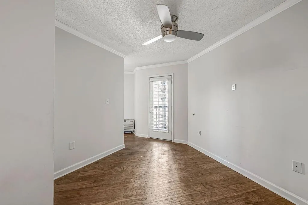 Spare room with dark wood-style floors, a textured ceiling, ornamental molding, and ceiling fan