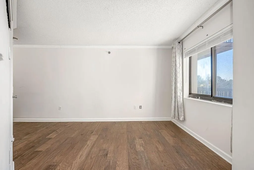Unfurnished room with dark wood-style flooring, a textured ceiling, and ornamental molding