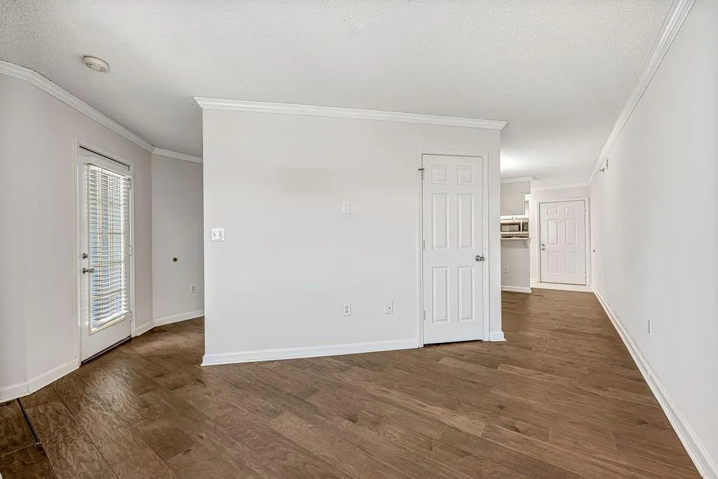 Spare room featuring crown molding, dark wood-style flooring, and a textured ceiling