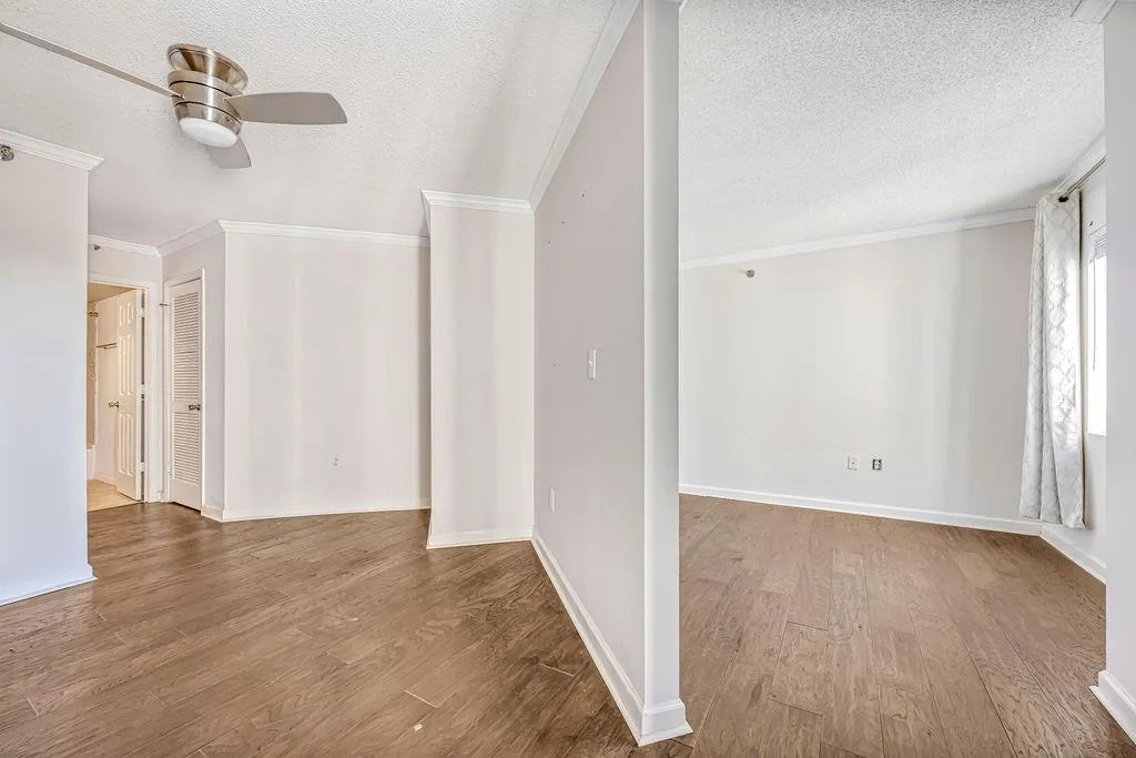 Empty room featuring crown molding, wood finished floors, a textured ceiling, and ceiling fan