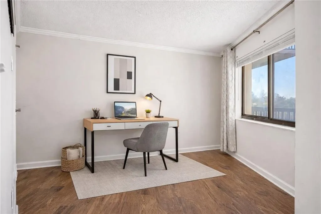 Office with a textured ceiling, dark wood-style floors, and ornamental molding