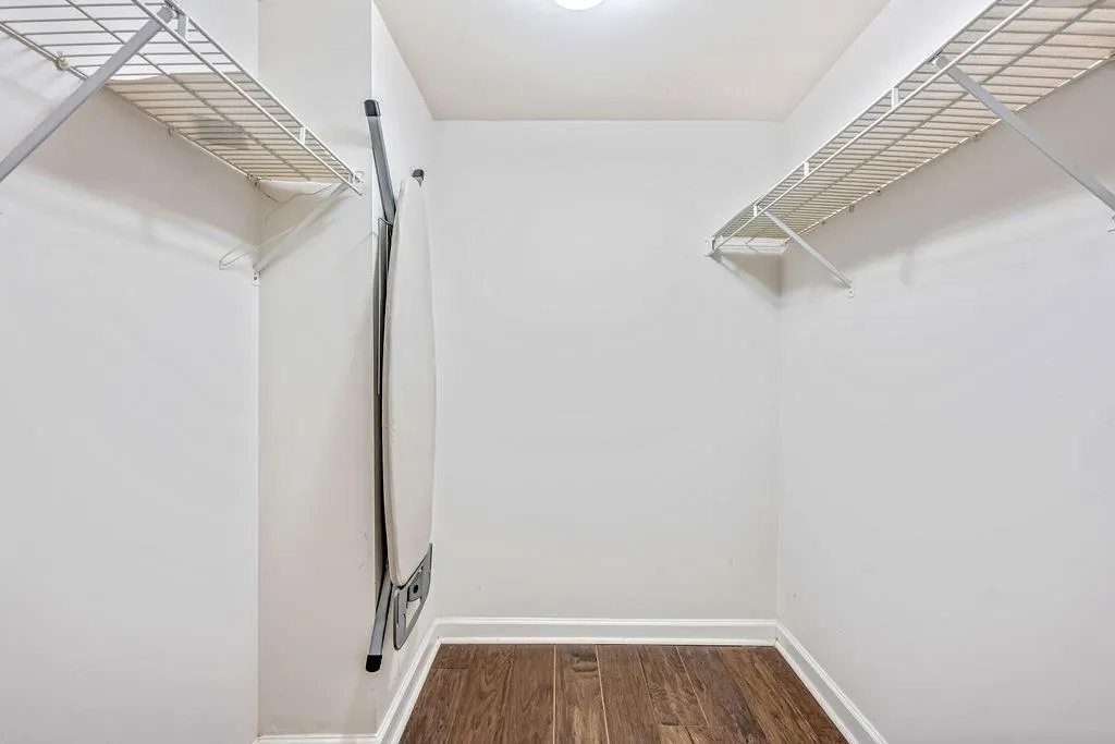 Walk in closet with dark wood-type flooring