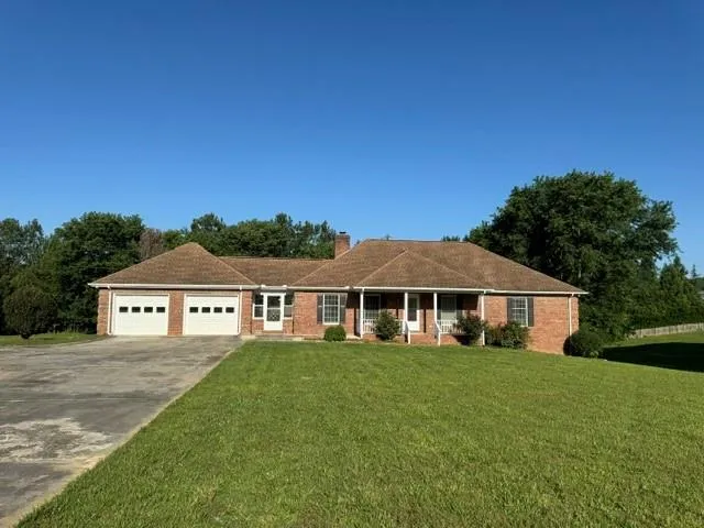 Brick ranch-style home featuring a two-car garage with individual doors, a covered front porch, and a shingle roof