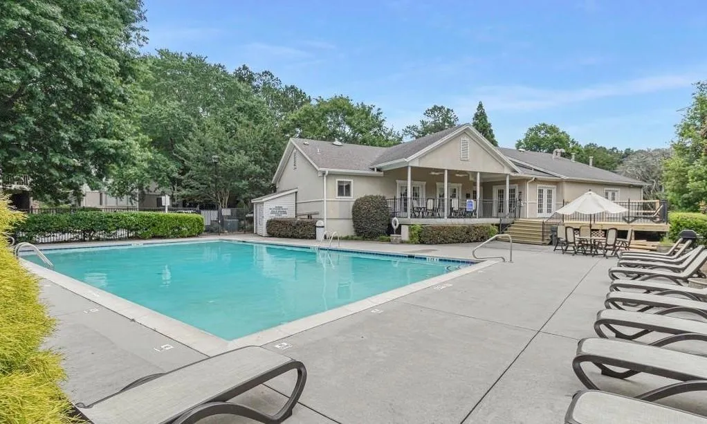 Community pool featuring a patio area and view of wooded area