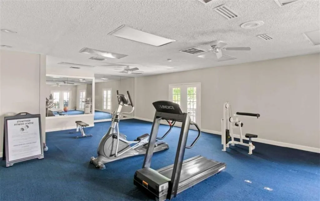 Exercise area featuring french doors, a ceiling fan, and a textured ceiling