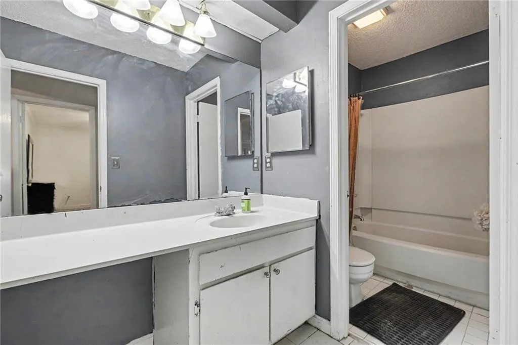 Full bathroom with vanity, a textured ceiling, shower / bath combination with curtain, and light tile patterned floors
