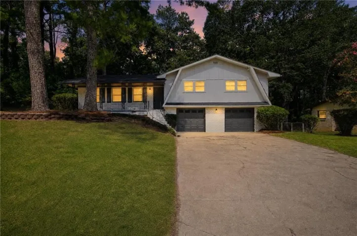Split-level residence featuring a two-car garage, mature trees, and a concrete driveway