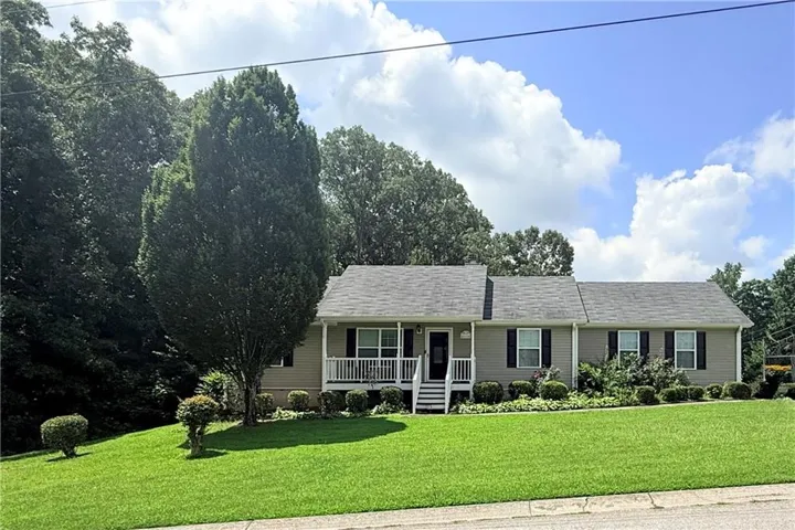 Ranch-style exterior with light beige siding, dark shingle roof, and black window shutters