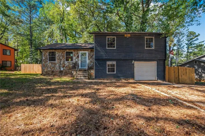 Split level home with an attached garage and stone siding