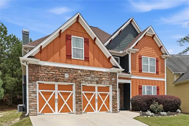 Craftsman-style exterior featuring a stone facade and contrasting orange siding
