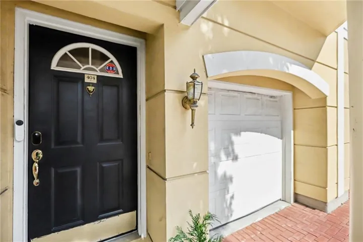 Black paneled entry door with an arched transom, brass hardware, and an adjacent wall-mounted lantern