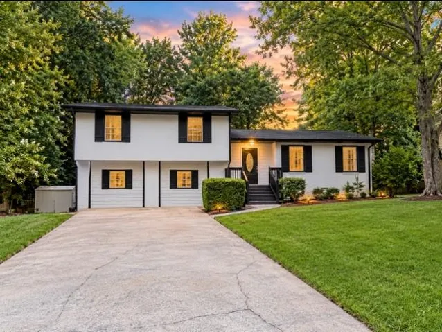 Split-level residence featuring a white exterior with black trim and shutters