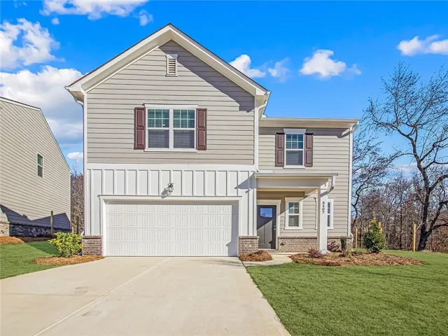 View of front of house featuring a garage, board and batten siding, a front lawn, and driveway