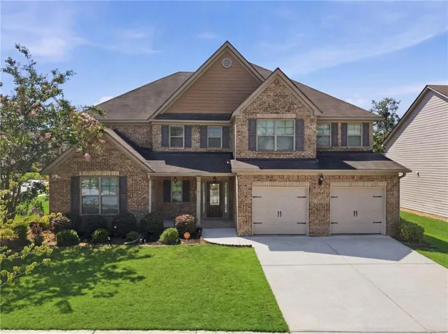 Traditional-style residence featuring a brick and siding facade, a two-car garage, and a concrete driveway