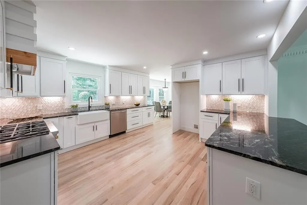 Kitchen featuring decorative backsplash, white cabinetry, light hardwood / wood-style flooring, and stainless steel dishwasher