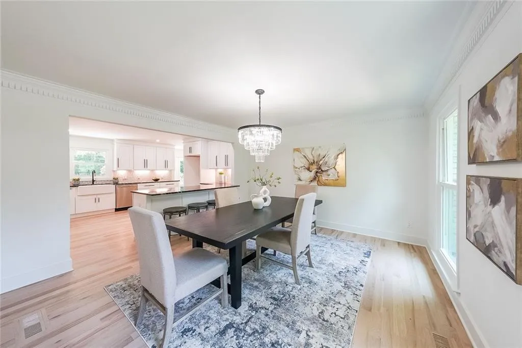 Dining room featuring an inviting chandelier, sink, crown molding, and light hardwood / wood-style floors