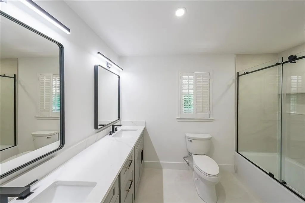 Full bathroom featuring tile patterned floors, toilet, enclosed tub / shower combo, and dual bowl vanity