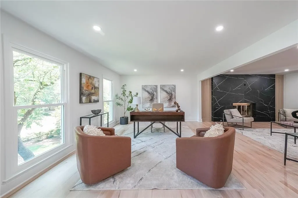 Living room with a healthy amount of sunlight, a high end fireplace, and light wood-type flooring