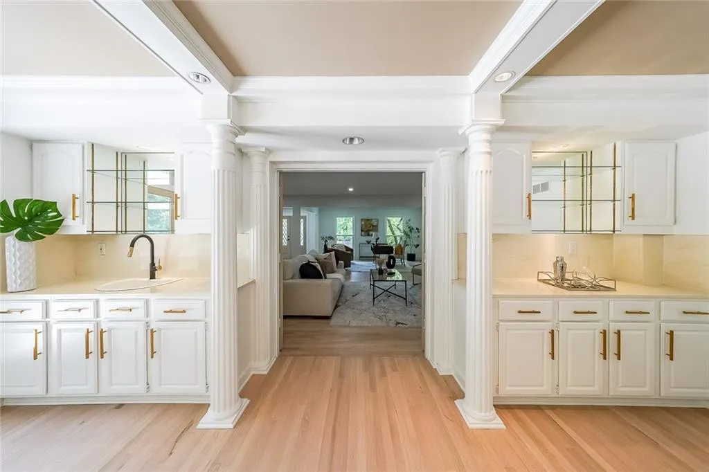 Hallway featuring sink, light hardwood / wood-style flooring, ornate columns, and a wealth of natural light