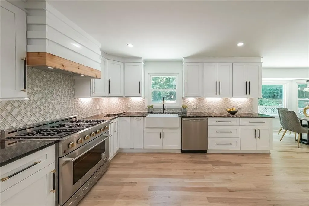 Kitchen featuring white cabinets, stainless steel appliances, dark stone countertops, and tasteful backsplash