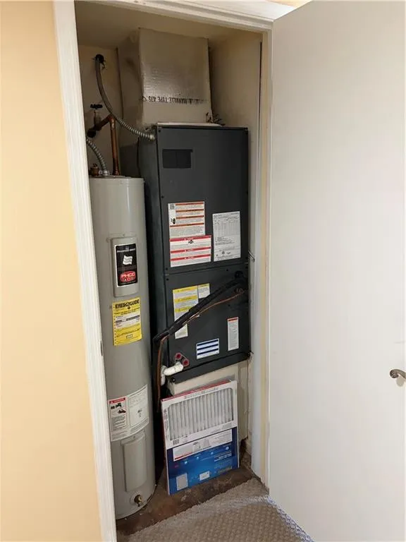 Utility room featuring water heater and heating unit