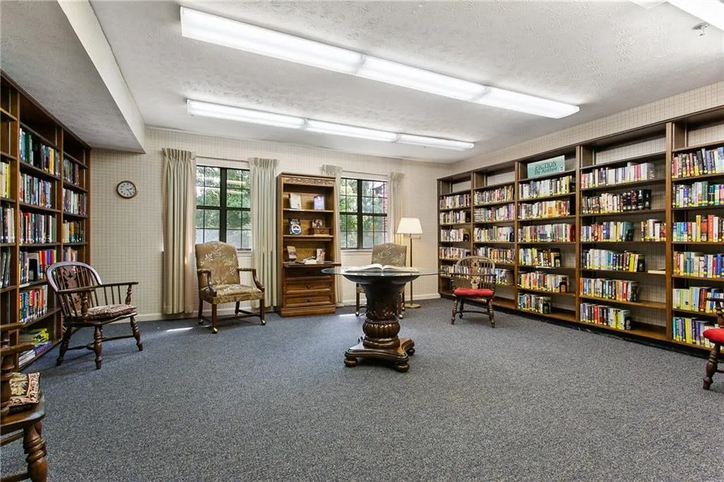 Sitting room featuring wall of books, a textured ceiling, and wallpapered walls