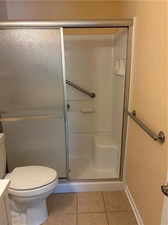 Full bathroom featuring a stall shower, light tile patterned flooring, and vanity