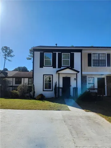 White exterior with black shutters, covered entry, and paved driveway