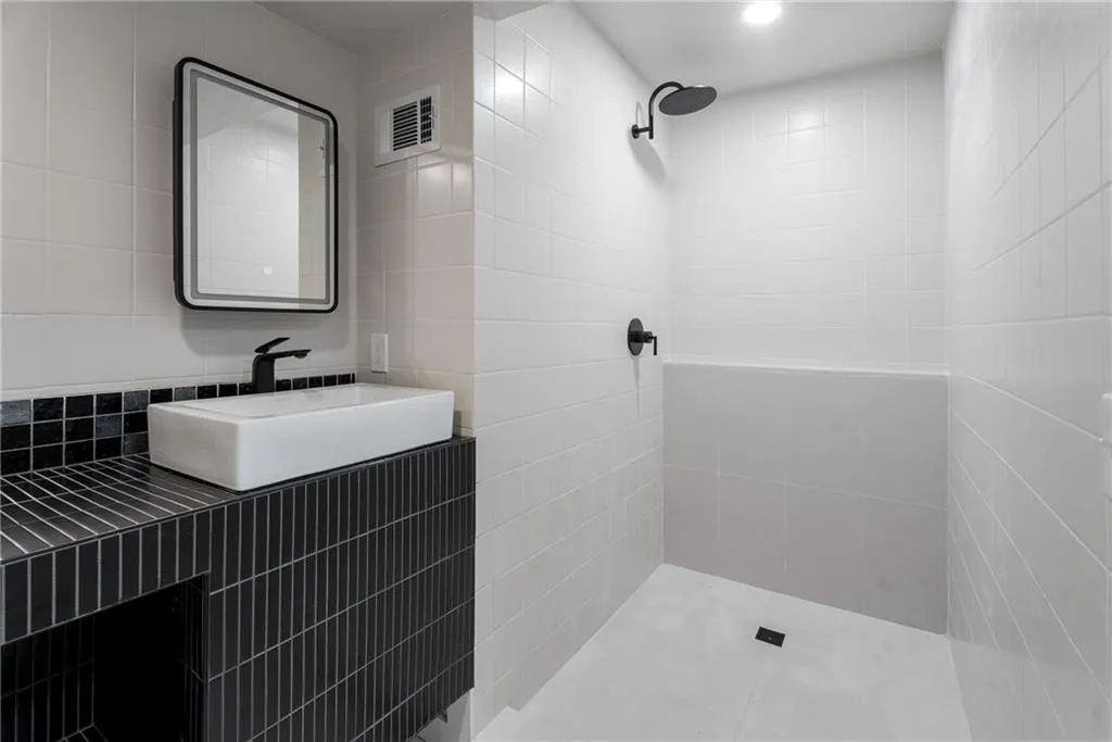 First/Guest bathroom featuring a bespoke vanity made of hand glazed clay tile and large shower with quartz tile and Kohler fixtures.