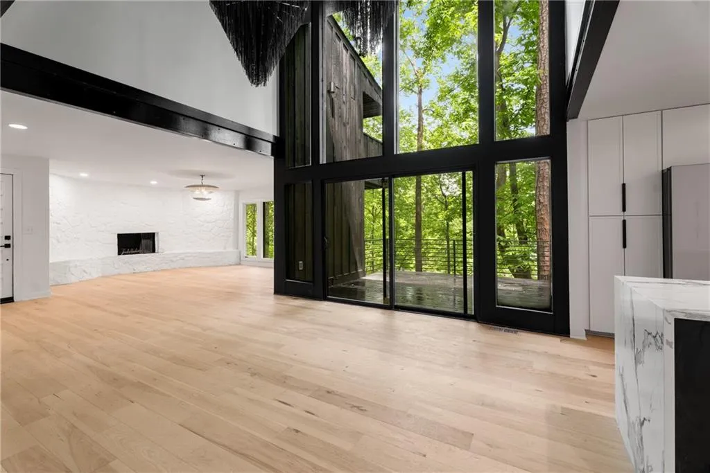 Light filled open concept layout with three story height ceilings, wide plank hardwood flooring, gorgeous chefs kitchen, wood burning fireplace and oversized deck, perfect for entertaining!