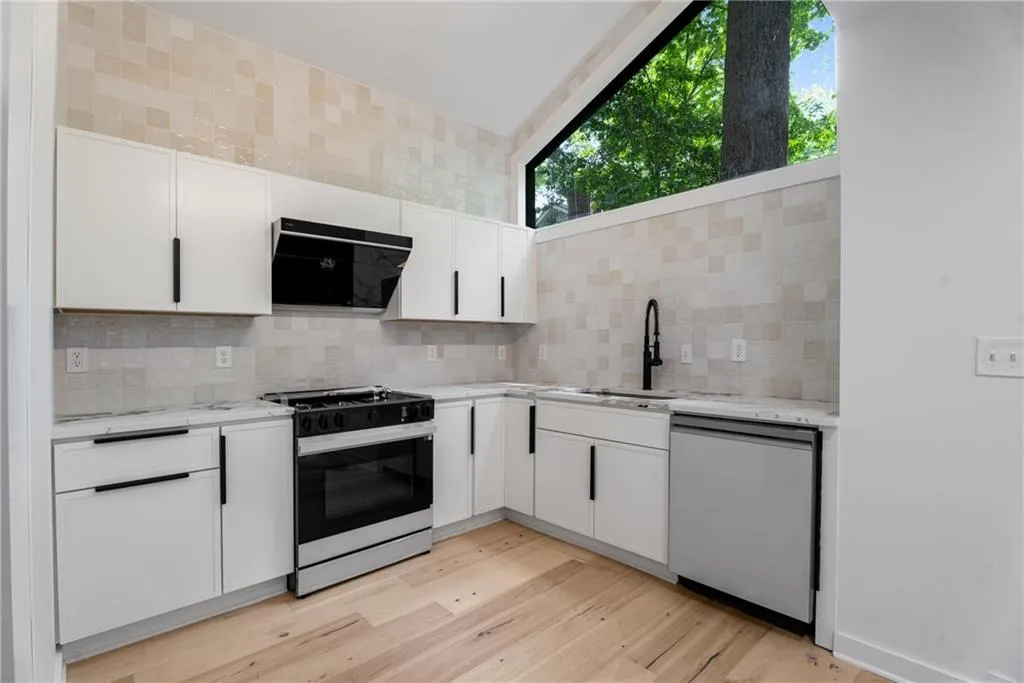Full wall hand glazed clay backsplash, smart appliances, gas range, commercial faucet and plenty of natural light in the working triangle of this chefs kitchen.