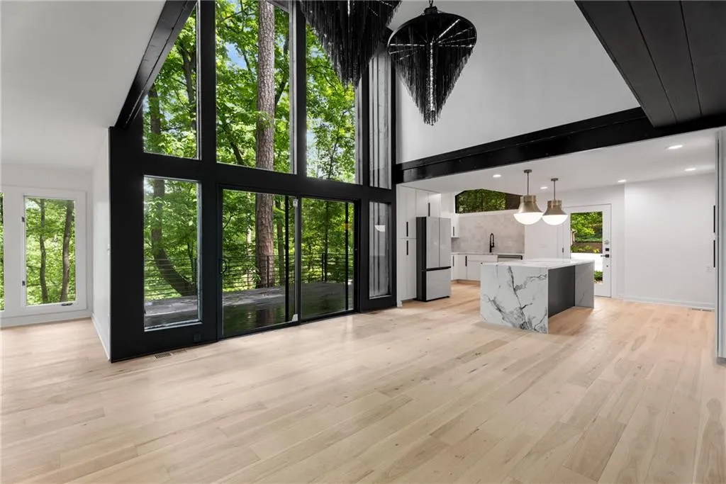 Light filled open concept layout with three story height ceilings, wide plank hardwood flooring, gorgeous chefs kitchen and lighting.