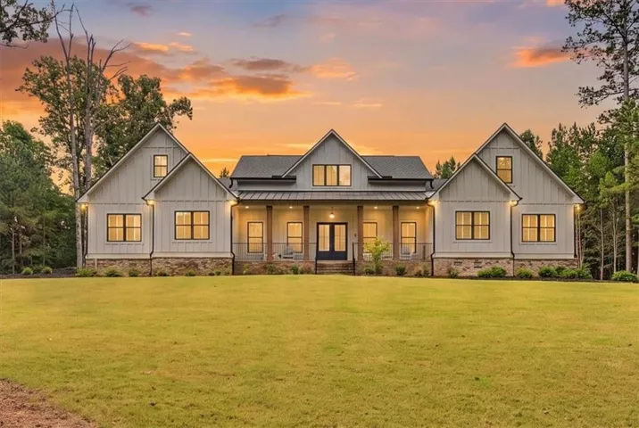 Modern farmhouse exterior featuring board and batten siding, stone accents, black-framed windows, a covered front porch, and a dormer window