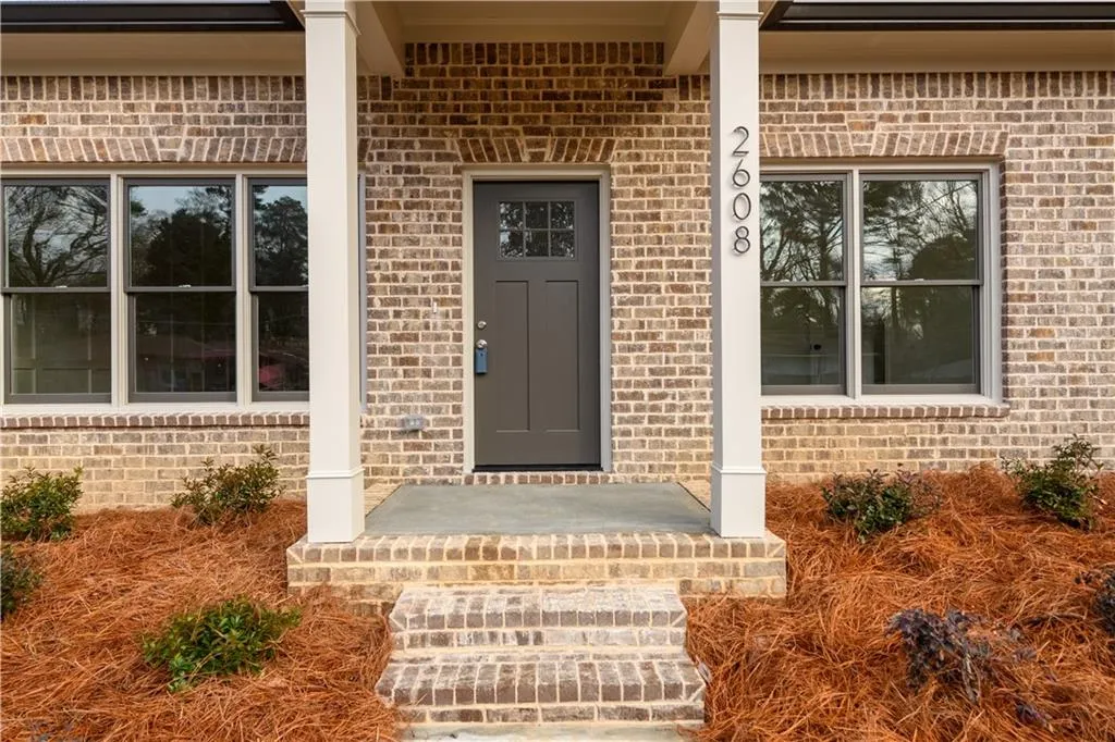 Entrance to property with brick siding and a porch