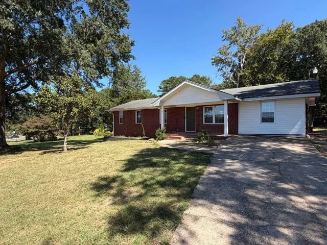 Brick and siding exterior with a concrete driveway and mature trees