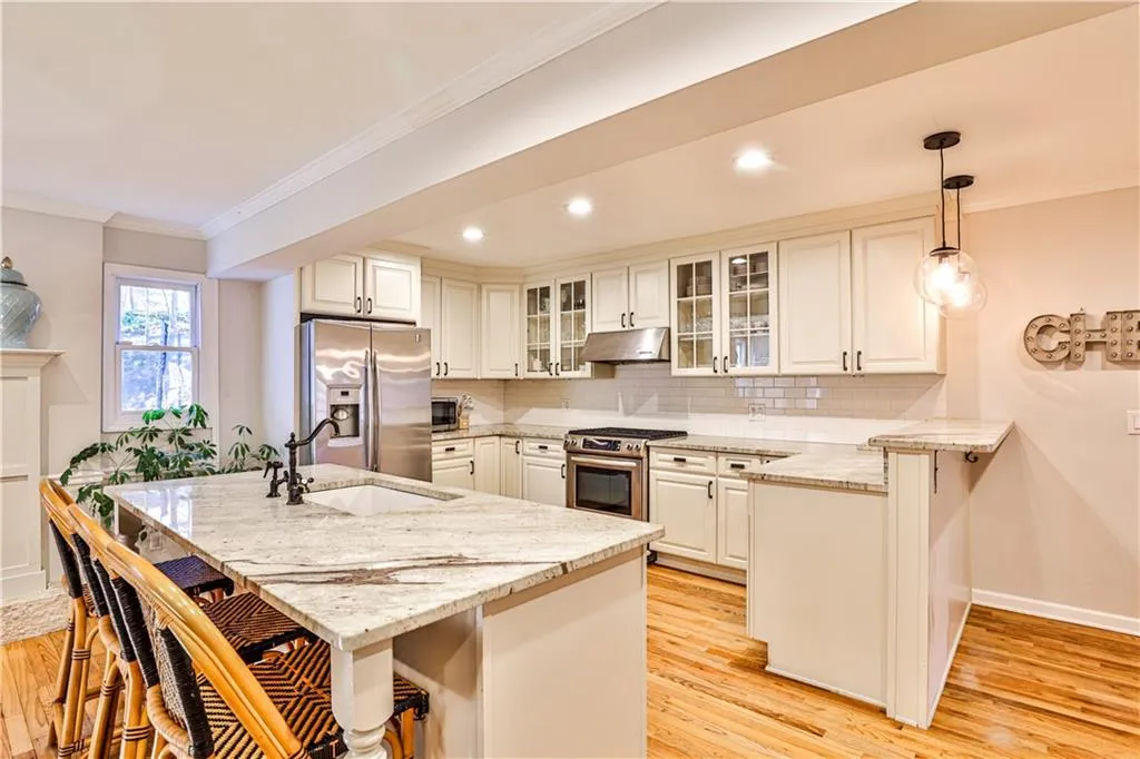 Kitchen with appliances with stainless steel finishes, white cabinetry, hanging light fixtures, a kitchen breakfast bar, and kitchen peninsula