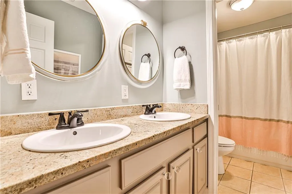 Full bathroom with tile patterned flooring, vanity, shower / bath combo, and toilet