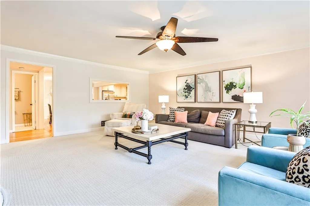Carpeted living room with ornamental molding and ceiling fan