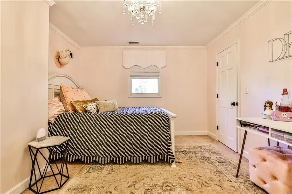 Bedroom featuring crown molding, light colored carpet, and a chandelier