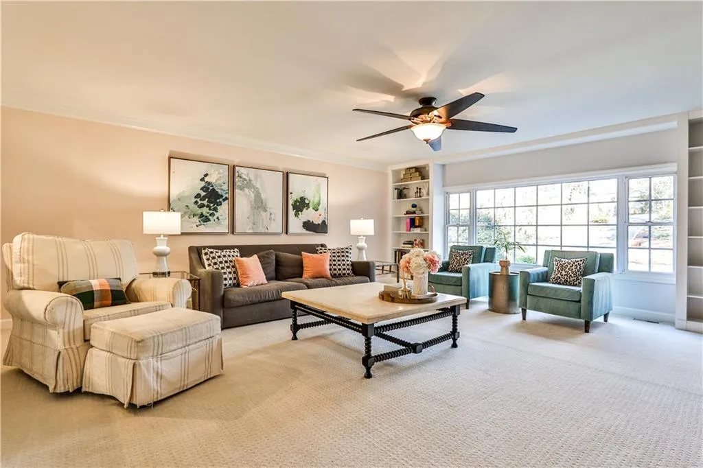 Living room featuring crown molding, built in features, ceiling fan, and carpet