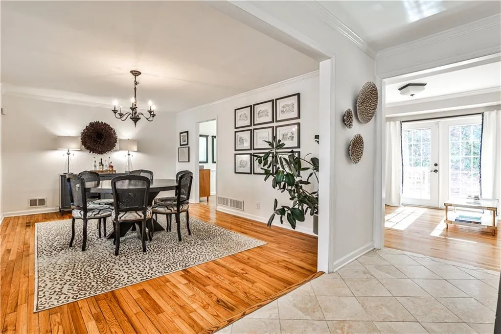 Dining space featuring ornamental molding, light tile patterned flooring, a notable chandelier, and french doors
