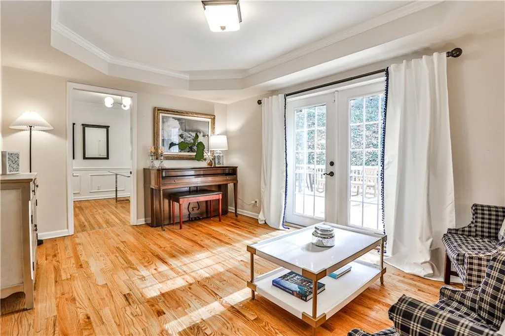 Living area with french doors, ornamental molding, a raised ceiling, and light hardwood / wood-style floors