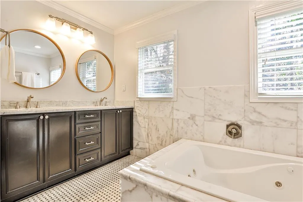 Bathroom featuring a relaxing tiled tub, ornamental molding, vanity, and tile walls