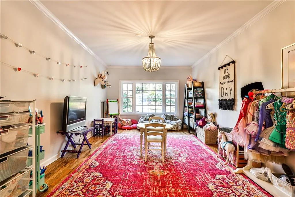 Living room featuring hardwood / wood-style floors, crown molding, and a notable chandelier