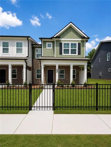 Charming two-story home featuring a sage green exterior with traditional architectural details, including a peaked roofline and brick accents