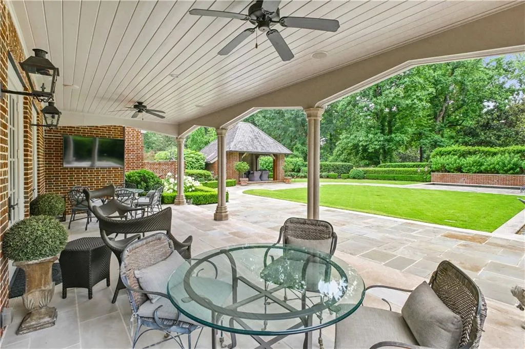 Expansive covered patio featuring a flagstone surface, beadboard ceiling, and multiple ceiling fans