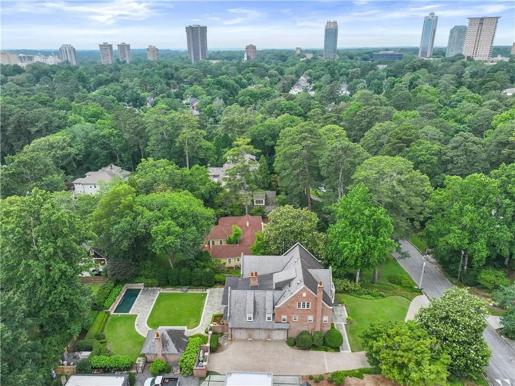 Brick residence with multi-car garage, extensive landscaping, and a rectangular swimming pool with surrounding patio