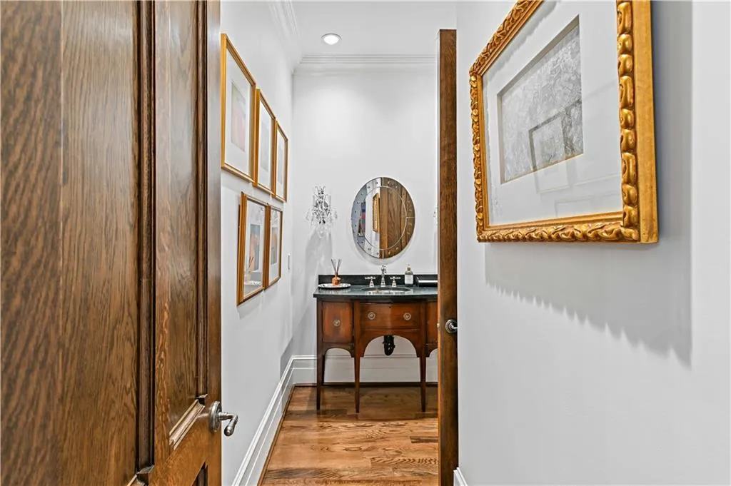 Powder room hallway featuring ornamental molding, wood finished floors, and recessed lighting
