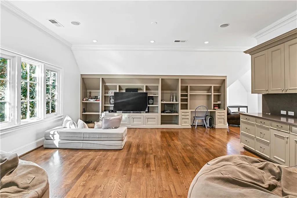 Living area with wood finished floors, crown molding, lofted ceiling, recessed lighting, and built in features