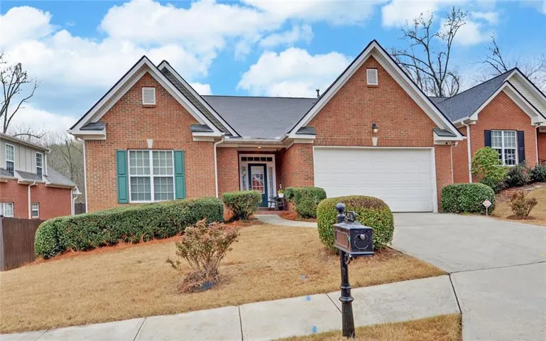 Traditional-style home with brick siding, driveway, a front lawn, and an attached garage